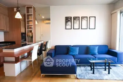 Modern living room with stylish blue sofa and open kitchen layout, perfect for contemporary living.