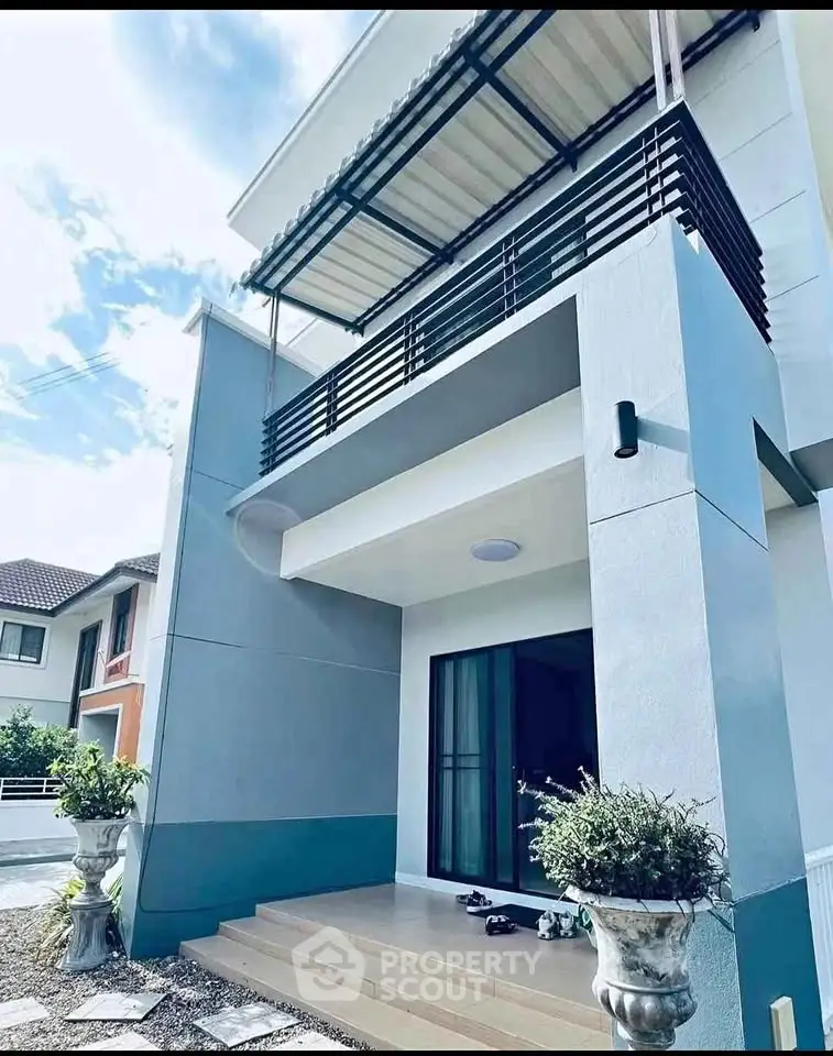 Modern two-story house with stylish balcony and entrance, featuring sleek design and contemporary architecture.