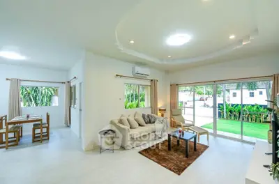 Spacious living room with modern decor and large windows overlooking lush greenery, perfect for relaxation.