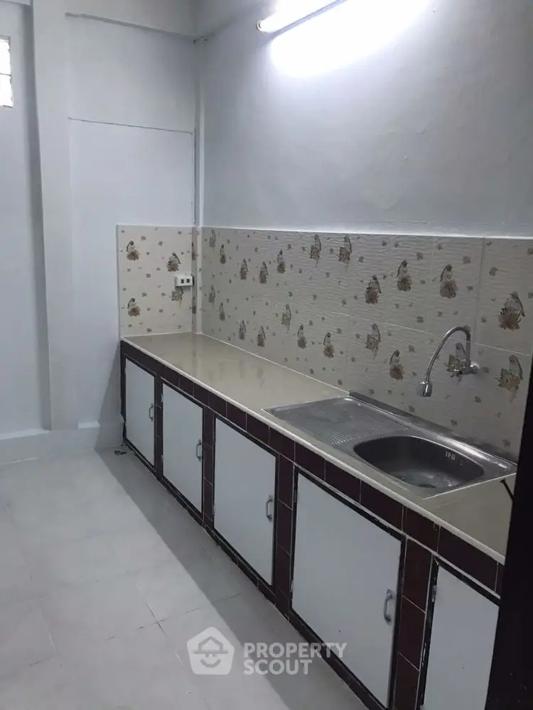 Cozy kitchen with tiled backsplash and modern sink in a minimalist design.