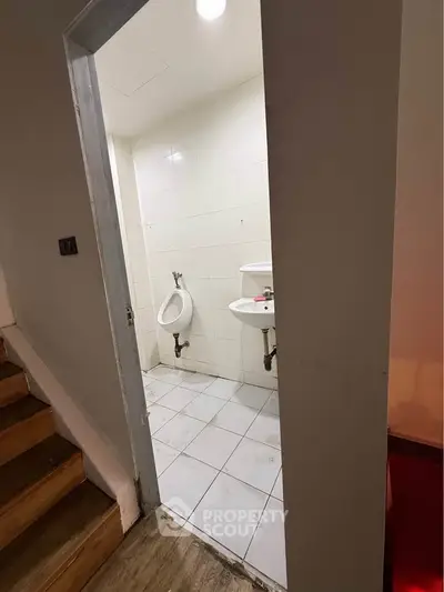 Compact bathroom with urinal and sink, ideal for commercial spaces.