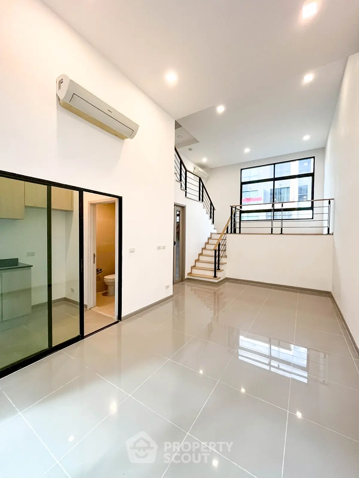 Spacious modern living room with high ceilings and sleek staircase in a contemporary home.