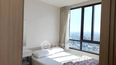 Bright bedroom with large window offering stunning city views, perfect for urban living.