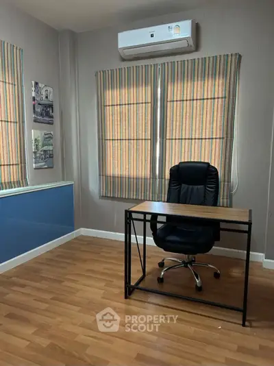 Modern study room with wooden flooring and stylish desk chair, perfect for productivity.