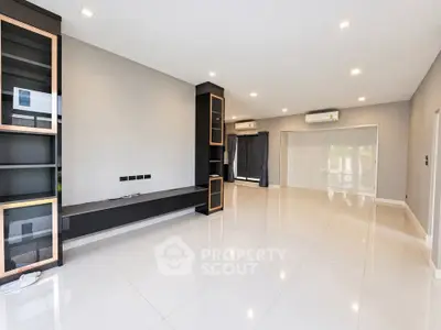 Spacious modern living room with sleek built-in shelving and glossy tile flooring.