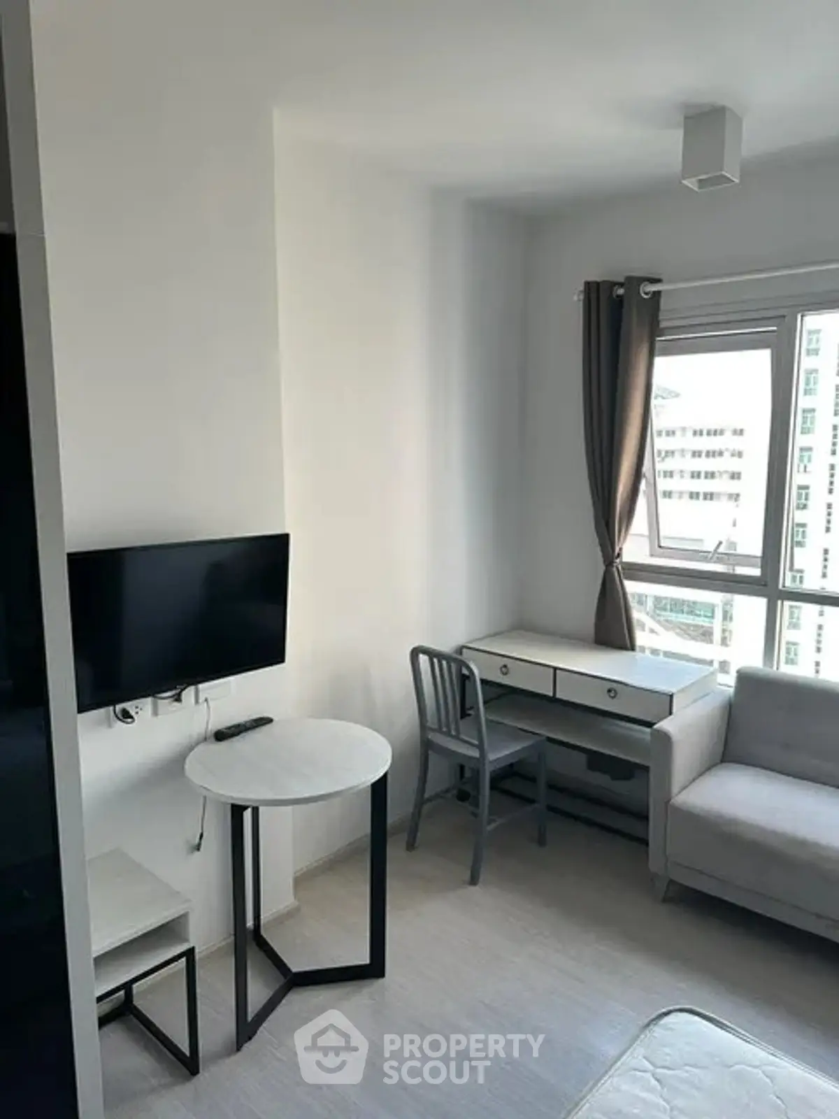 Modern studio apartment with natural light, featuring a cozy living area and workspace.