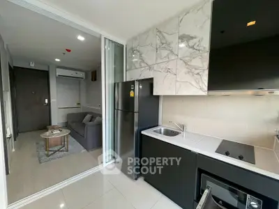 Modern open-layout kitchen with sleek appliances and cozy living area in a stylish apartment.