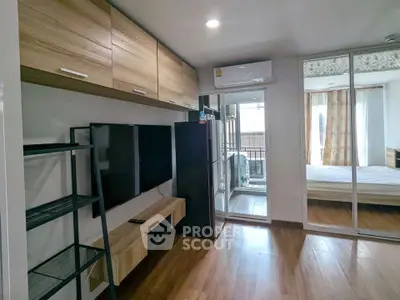 Modern apartment interior with wooden flooring, sleek TV setup, and balcony access.