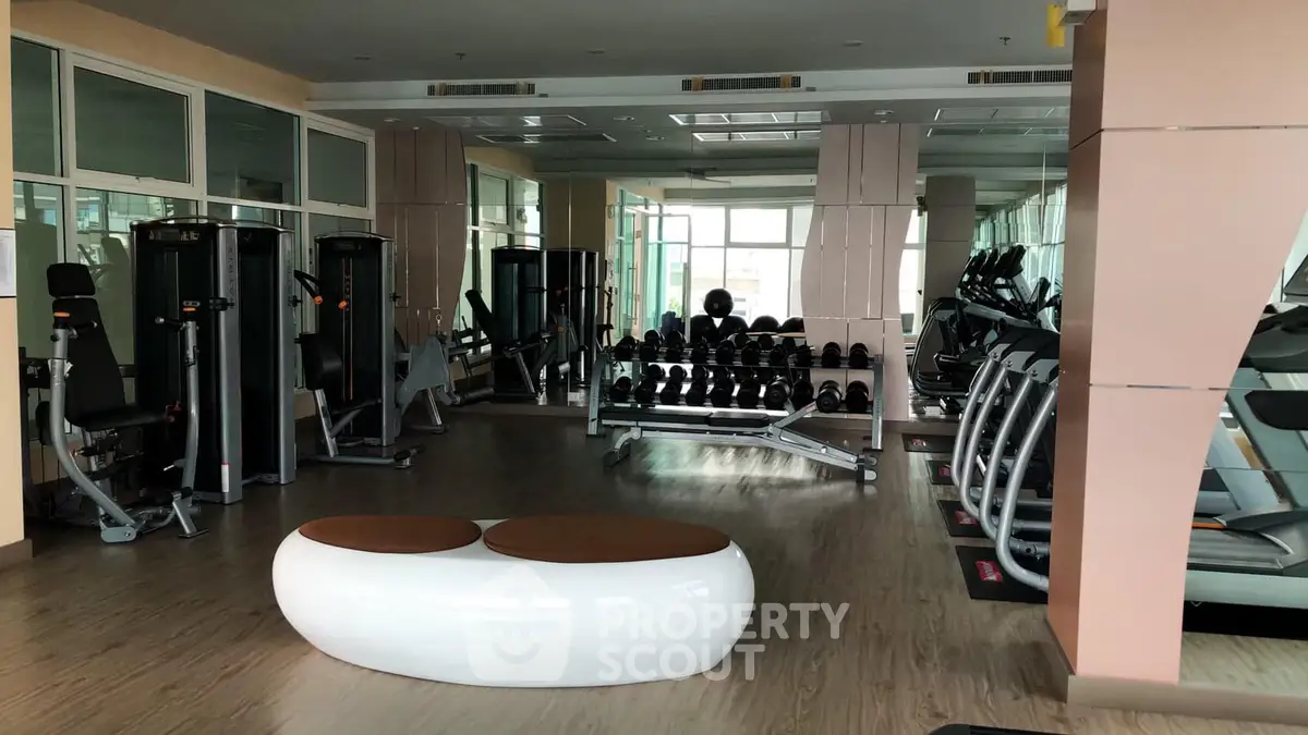 Spacious gym with modern equipment and mirrored walls in luxury real estate property.