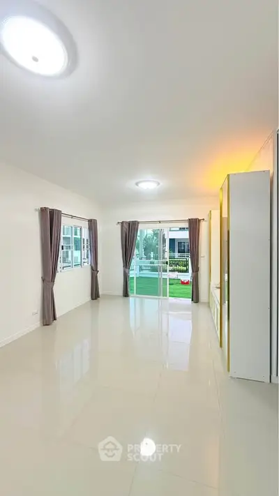 Spacious living room with large windows and elegant curtains, offering a bright and airy atmosphere.
