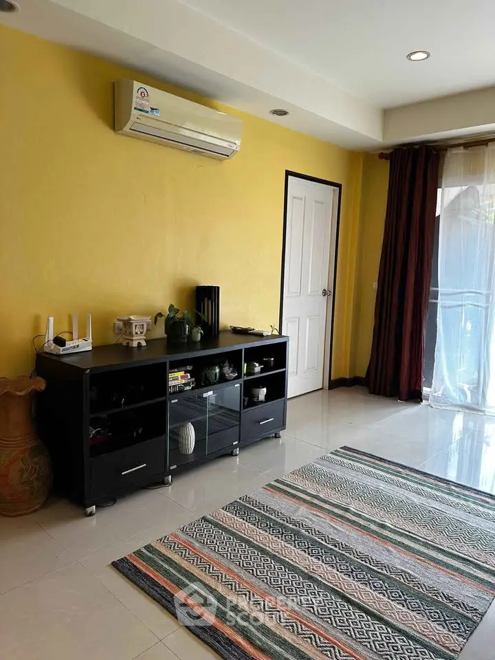 Bright living room with yellow walls, modern furniture, and natural light from large windows.