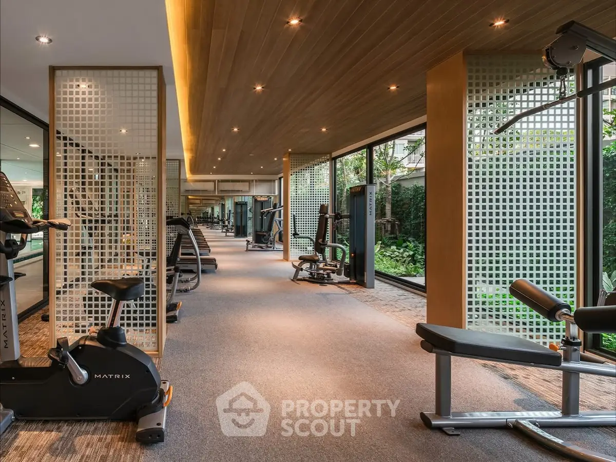 Luxurious gym with modern equipment and garden view in upscale residential building.