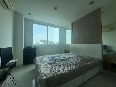 Modern bedroom with large window and stylish decor in a high-rise apartment.