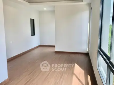 Spacious empty room with large windows and wooden flooring, perfect for customization.