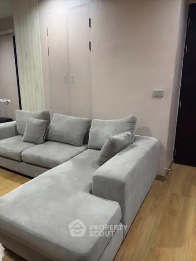 Spacious modern living room with stylish gray sectional sofa and wooden flooring