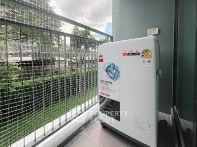 Modern balcony with washing machine and lush green view, perfect for urban living convenience.