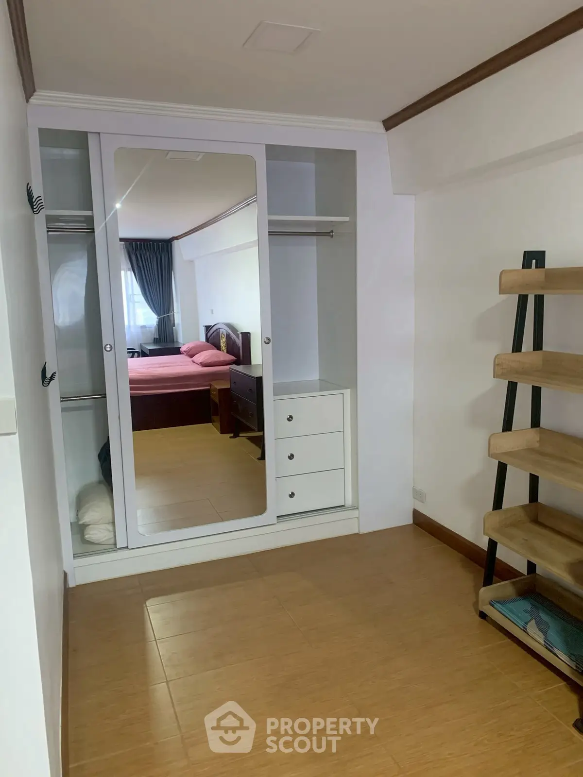 Spacious bedroom with mirrored wardrobe and wooden flooring, ideal for modern living.
