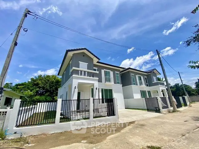 Modern two-story house with spacious driveway and fenced yard under clear blue sky.