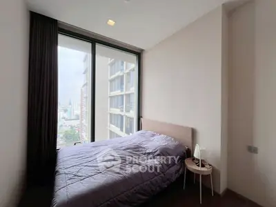 Cozy bedroom with large window offering city view in modern apartment