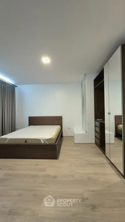 Spacious modern bedroom with wooden flooring and large wardrobe