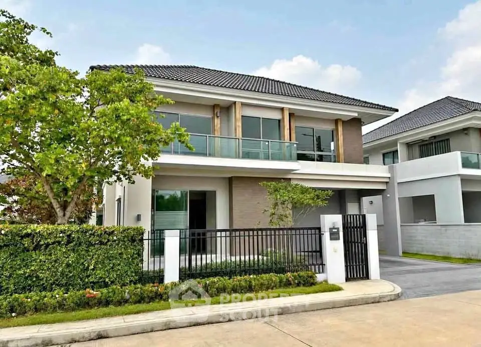 Modern two-story house with large windows and landscaped garden in a serene neighborhood.