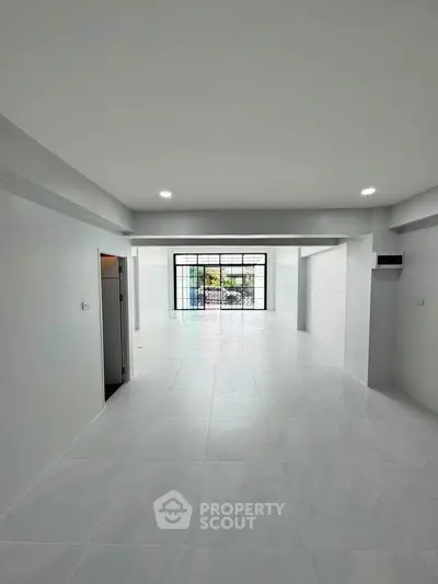 Spacious open-plan interior with large windows and modern flooring, ideal for versatile living or office space.