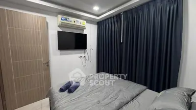 Cozy bedroom with modern amenities and stylish decor, featuring a wall-mounted TV and air conditioning.