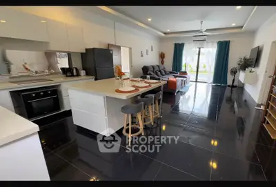 Spacious modern open-plan kitchen and living room with sleek black flooring and stylish furnishings.