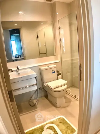 Modern bathroom with glass shower, sleek sink, and toilet, featuring a stylish mirror and neutral color palette.