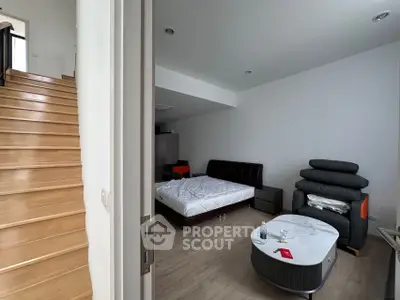 Modern bedroom with sleek furniture and wooden staircase, ideal for contemporary living.