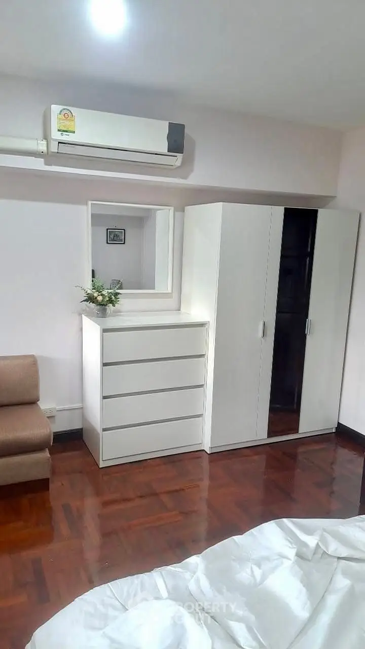Cozy bedroom with modern white furniture and air conditioning, perfect for comfortable living.