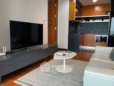 Modern living room with sleek TV unit and open kitchen layout in stylish apartment.