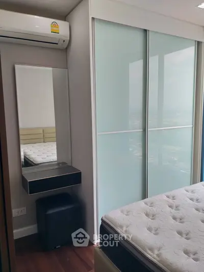 Modern bedroom with large window and built-in wardrobe, featuring a comfortable mattress and air conditioning.