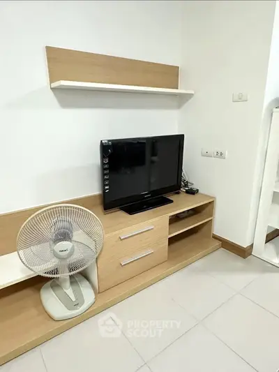 Modern living room with TV, fan, and sleek wooden furniture in a cozy apartment.