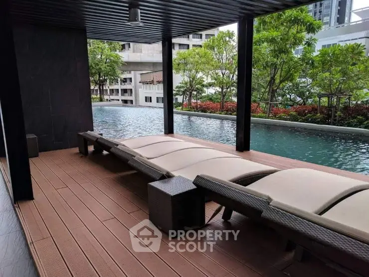 Luxurious poolside area with modern lounge chairs and lush greenery in a high-end residential complex.