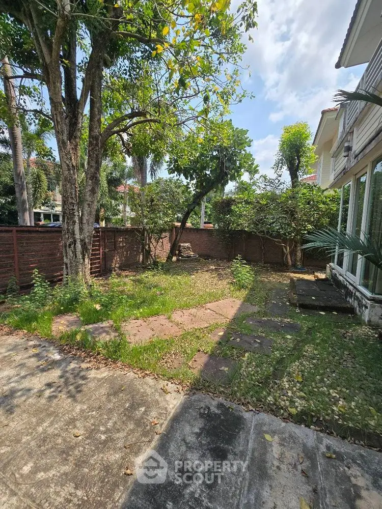 Charming garden with lush greenery and paved walkway in a serene residential area.