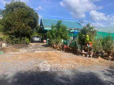 Charming rural property with lush garden and spacious driveway under a clear blue sky.