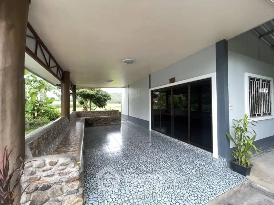 Spacious covered patio with tiled flooring and garden view, perfect for outdoor relaxation.