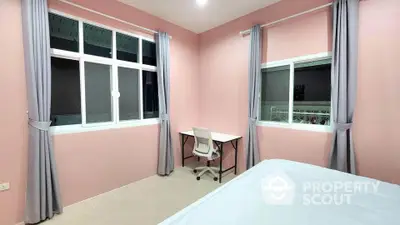 Cozy bedroom with pink walls, large windows, and a study desk, perfect for relaxation and productivity.