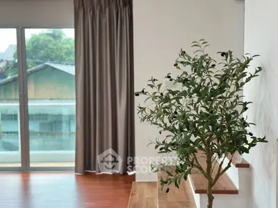 Bright interior with wooden floors, large window, and potted plant, perfect for modern living.