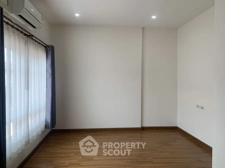 Spacious empty room with wooden flooring and large window