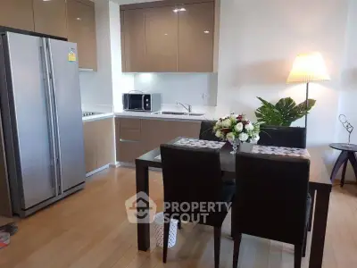 Modern kitchen with dining area, featuring sleek cabinets and stainless steel appliances.