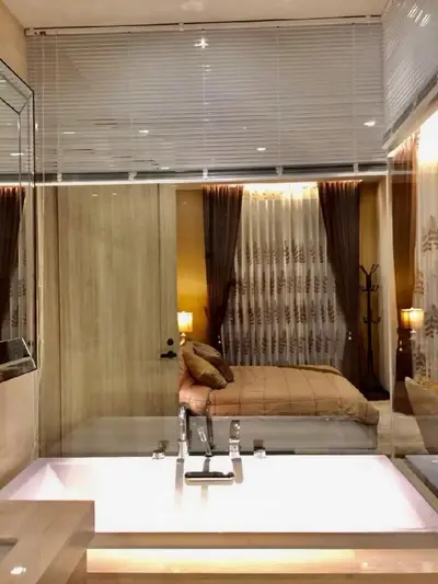 Luxurious bathroom with a view into a cozy bedroom, featuring elegant decor and ambient lighting.