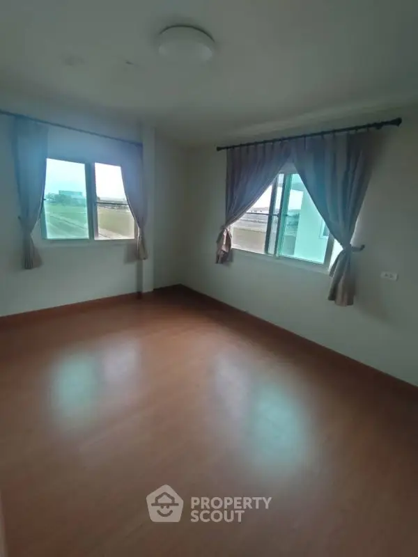 Spacious empty room with large windows and wooden flooring, perfect for customization.
