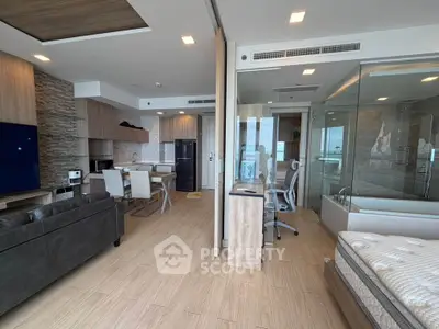 Modern open-plan living room with kitchen and bedroom, featuring stylish decor and natural light.