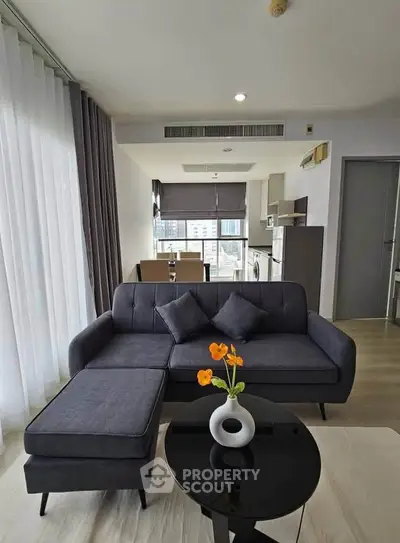 Modern living room with stylish furniture and open kitchen layout in a high-rise apartment.
