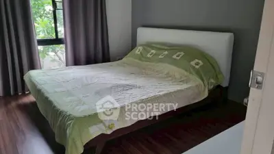 Cozy bedroom with large window and stylish decor, perfect for relaxation.