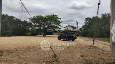 Spacious vacant land with potential for development, surrounded by greenery and residential homes.