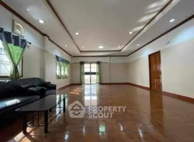 Spacious living room with wooden flooring and modern lighting, ideal for family gatherings.