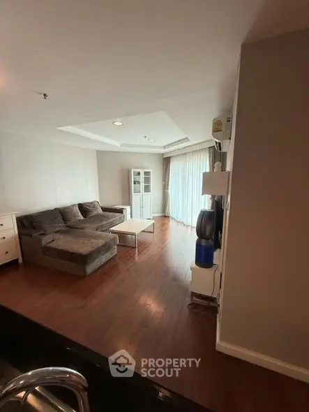 Spacious living room with wooden flooring and cozy sofa in modern apartment.